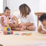 On a holiday, A mother and her two little daughters sit on the floor and drawing together in the living room