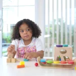 A little girl sit on the floor sit on the floor and play the toy